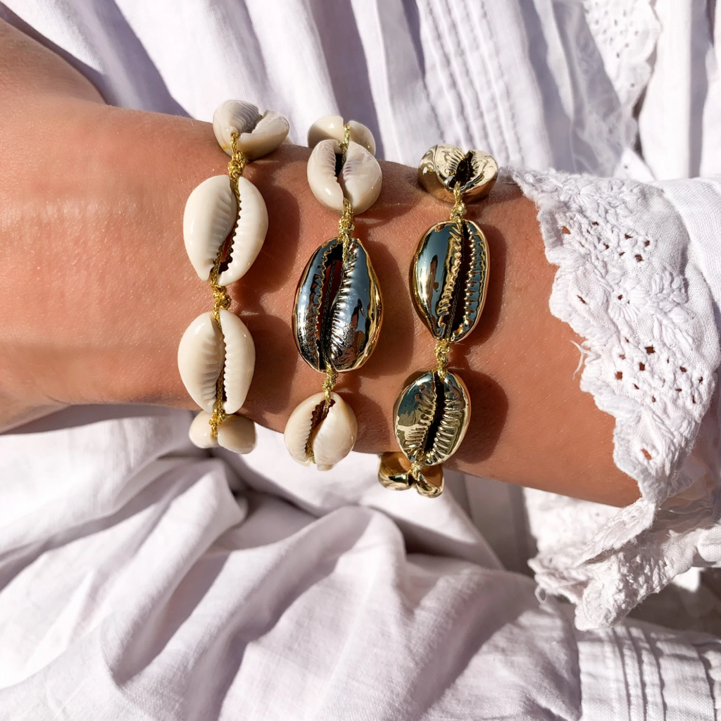 single gold cowry shell with several natural cowrie shells on bracelet